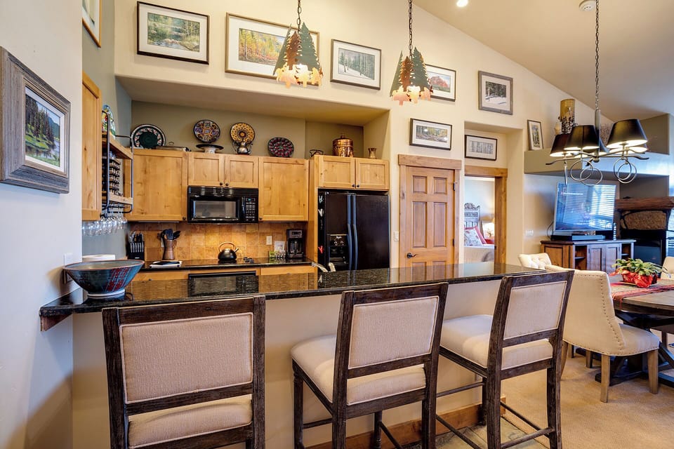 Gather around the breakfast bar in your spacious, mountain-themed kitchen, where rustic charm meets modern convenience. With soaring ceilings and a warm glow, this inviting space is perfect for sharing meals and making memories together.