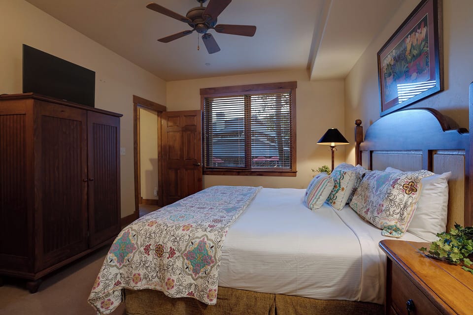 Sink into your inviting bed with crisp linens and colorful accents. A ceiling fan and warm wood furnishings create a cozy retreat where you can unwind after exploring.