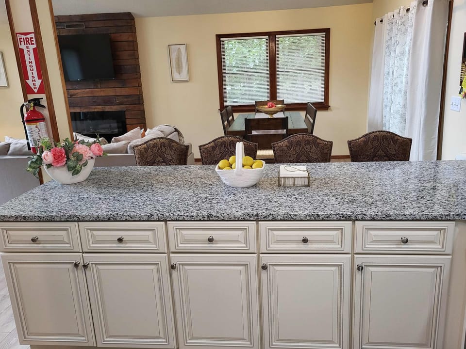 A well-stocked kitchen island with a Keurig station, fresh flowers, and a lemon basket, just steps from the dining table.