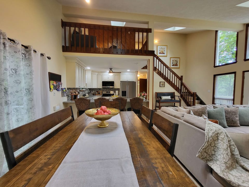 A soaring two-story living space with a loft overlook, staircase, and open sightlines straight into the kitchen.