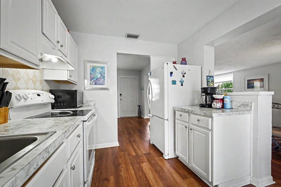 Full kitchen with white cabinetry, stove and full-size refrigerator