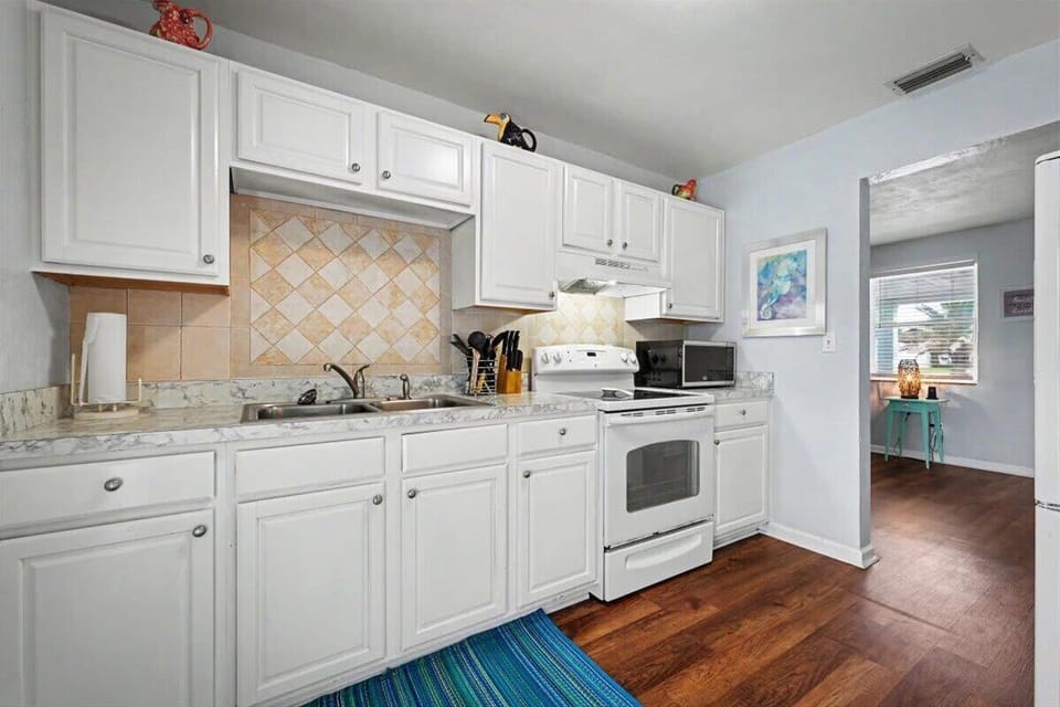 Full kitchen with white cabinetry, electric range and generous counter space