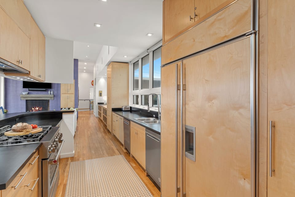 A streamlined galley kitchen pairs generous counter space with a professional-style range, double sink, and a separate prep nook beyond.