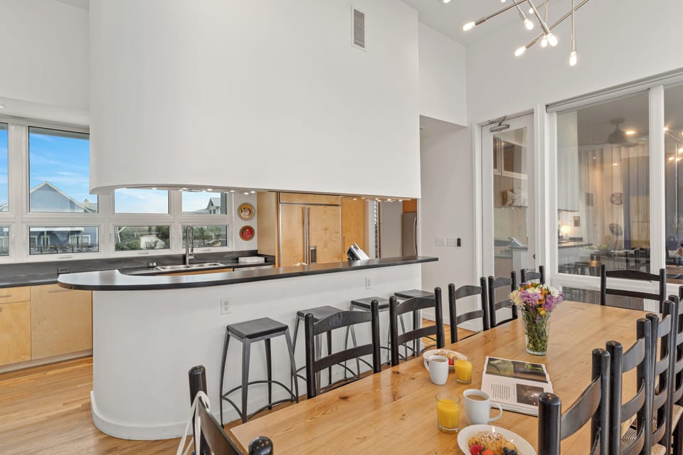 A long dining table offers plenty of room for group meals, with a pass-through bar keeping the kitchen connected to the gathering space.