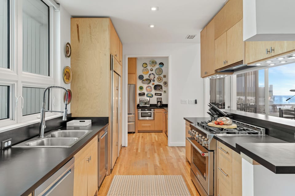 A streamlined galley kitchen pairs generous counter space with a professional-style range, double sink, and a separate prep nook beyond.