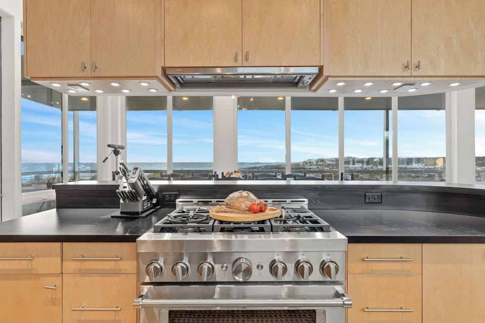 A streamlined galley kitchen pairs generous counter space with a professional-style range, double sink, and a separate prep nook beyond.