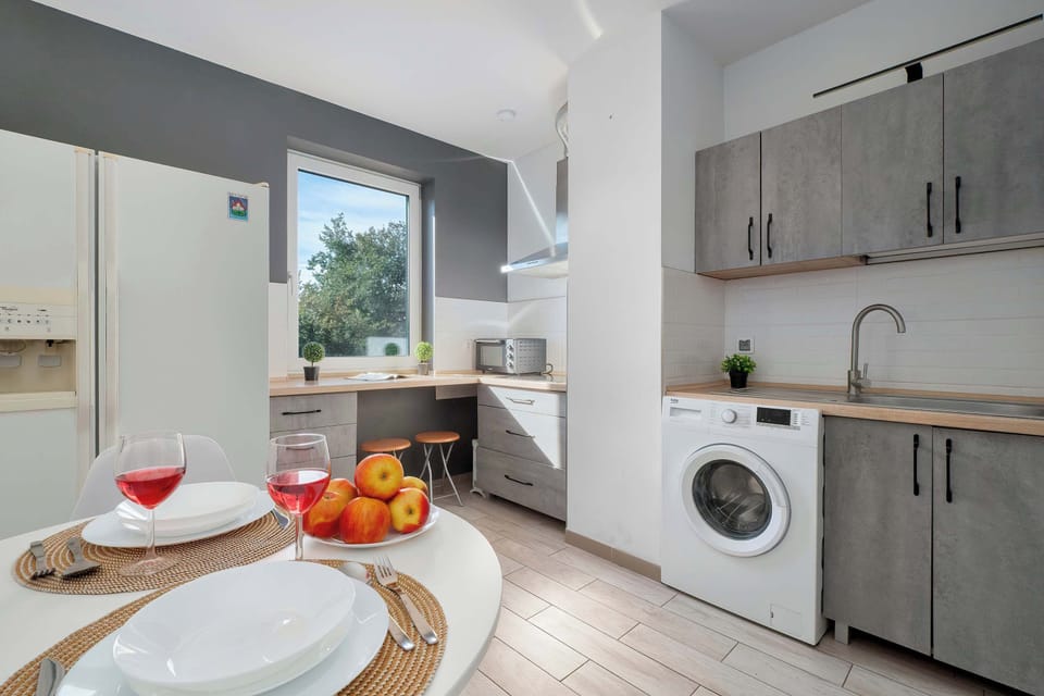 Stylish open-plan kitchen with modern grey cabinets, a dining table, and a washing machine.