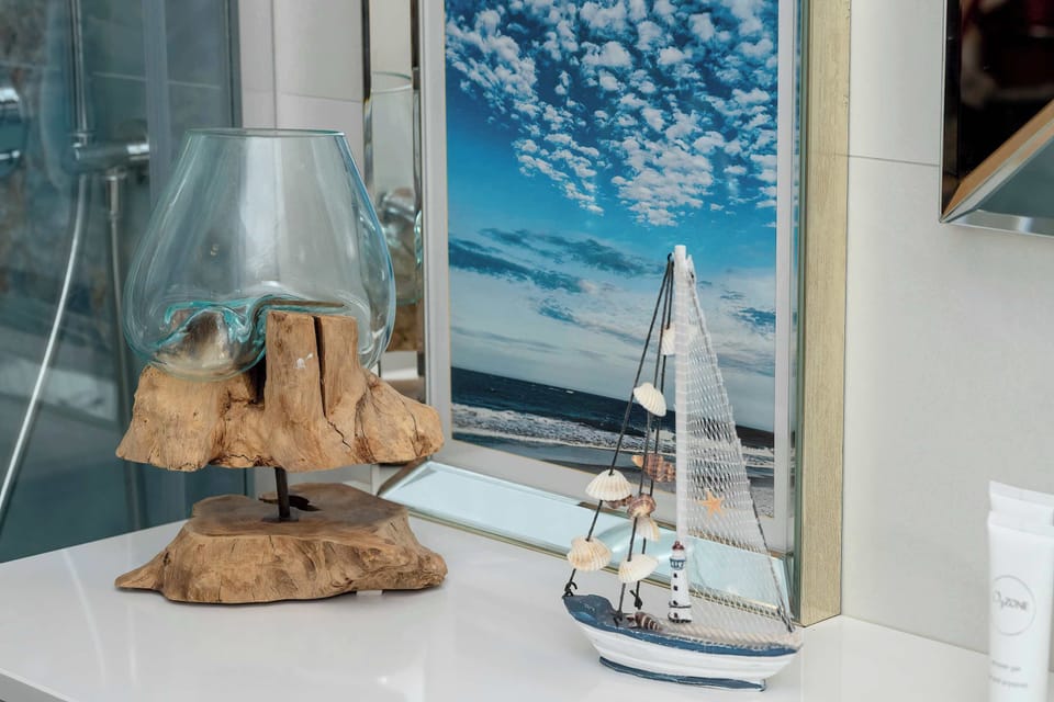 A bathroom decorated with coastal-inspired details, including a model sailboat, seashells, and a decorative lighthouse. The arrangement adds a charming seaside character to the space.