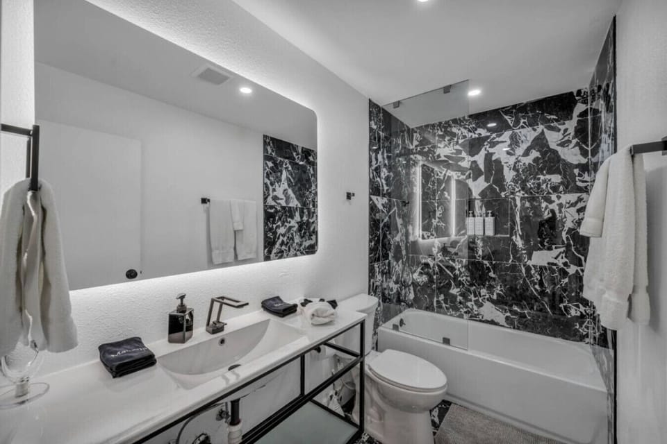 Guest Full Bathroom located on the second floor, Bathtub combined with Head-shower Unwind in this sleek, modern bathroom featuring striking marble tile, a glowing backlit mirror, and a spacious tub-shower combo—where luxury meets comfort.