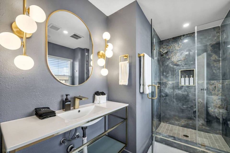 Master Private Full Bathroom  Step into spa-like luxury with this sleek bathroom featuring a striking walk-in shower, elegant gold fixtures, and soft lighting that sets the perfect mood for relaxation. Organic shampoo, conditioner and body wash we ar
