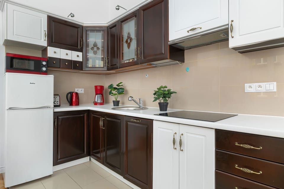 The kitchenette features a clean, functional design with a mix of dark wood and white cabinetry. Built-in appliances and ample counter space make the area highly suitable for cooking.