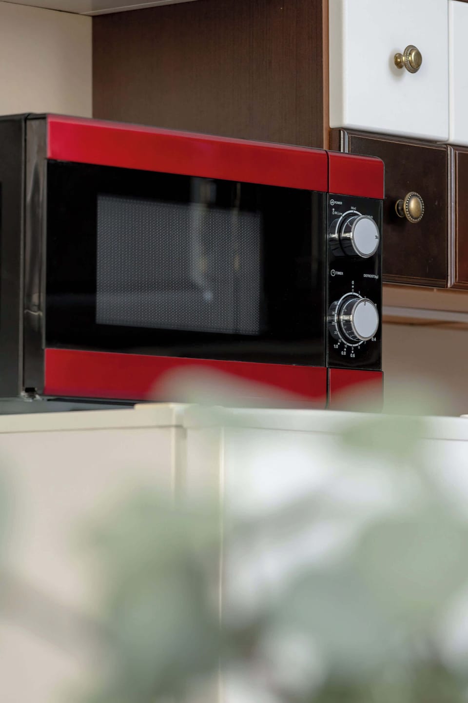 A close-up view focuses on a red microwave oven integrated into the kitchen cabinetry. The bright red appliance contrasts sharply with the surrounding neutral tones.