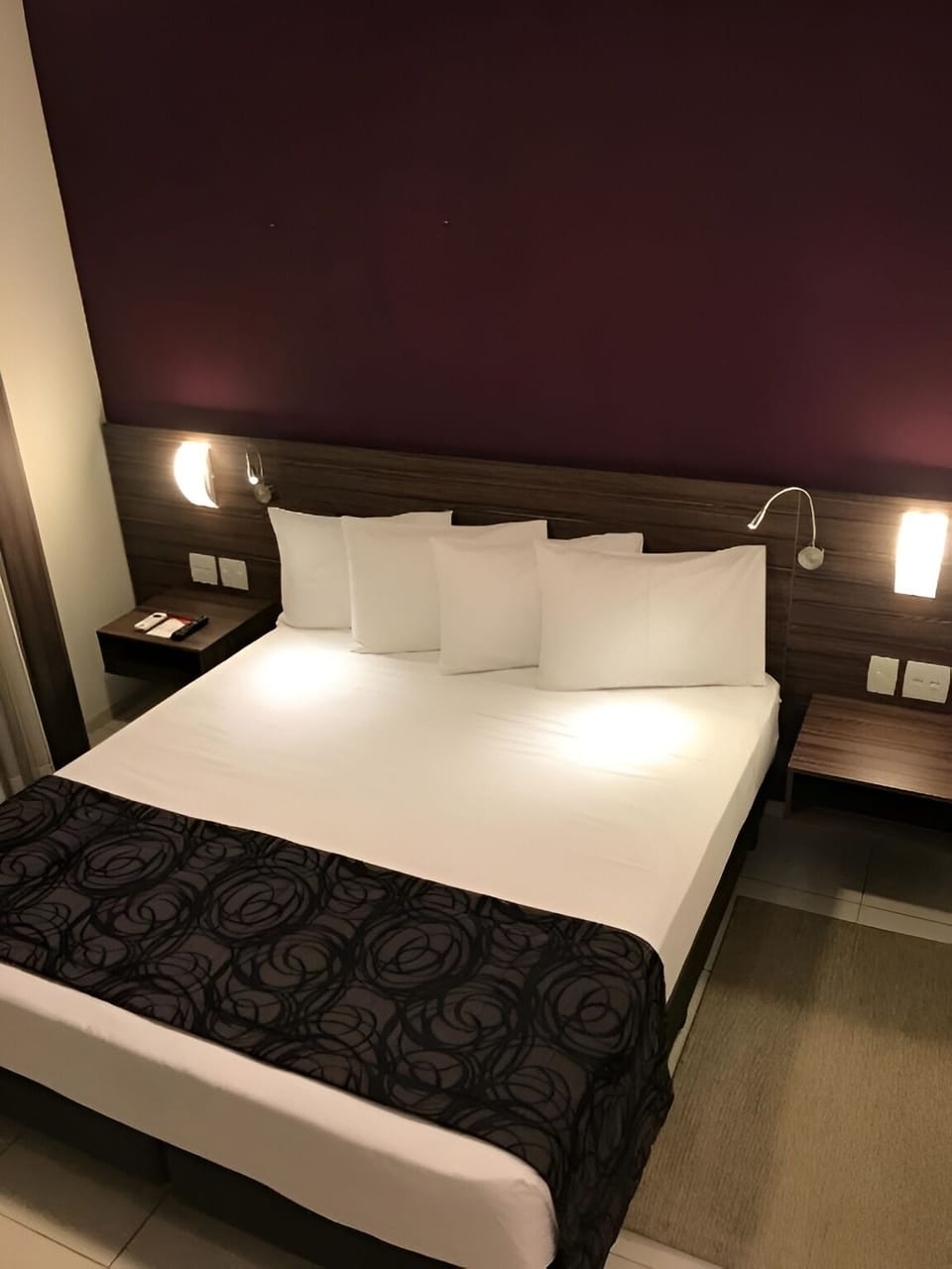 Sink into crisp linens beneath warm, modern bedside lighting.