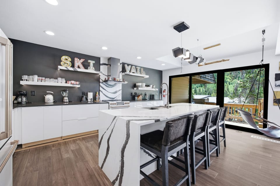 Contemporary gourmet kitchen with waterfall island and scenic deck views