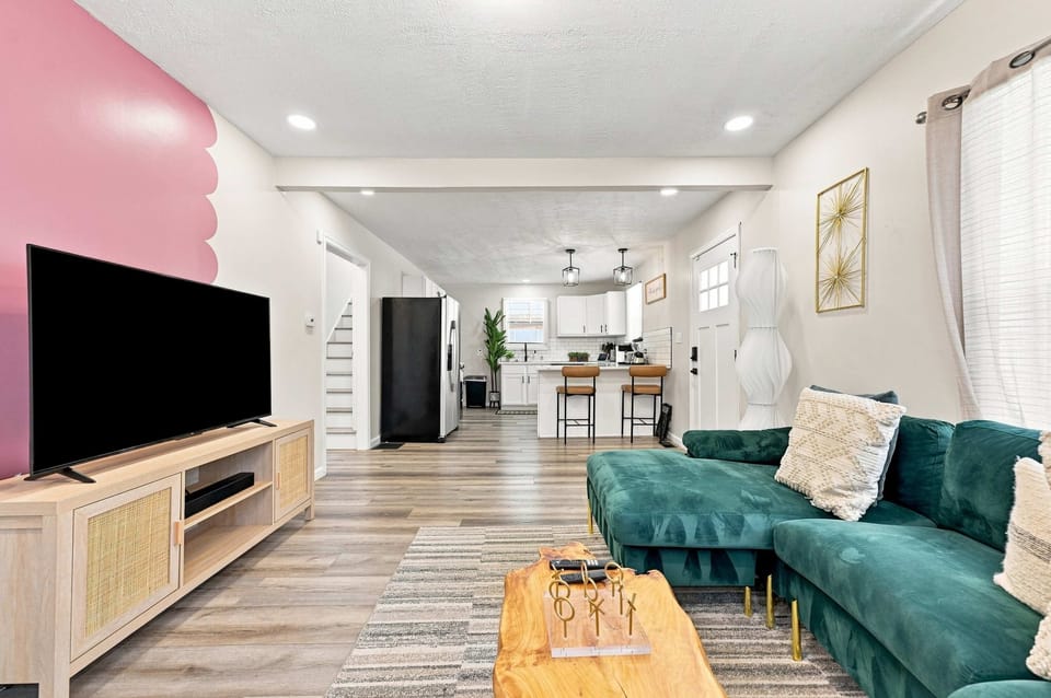 A bright, welcoming living room with colorful details, comfortable seating, and a Smart TV