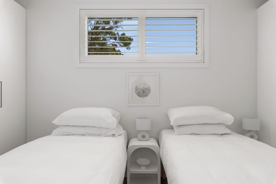 Bright twin room with crisp linens, natural light, and modern coastal style
