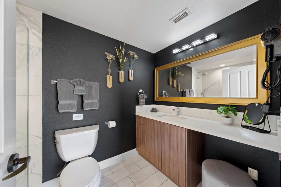 🛁 Dark, moody bath with a gold-framed mirror—a dressing area with boutique-hotel polish.