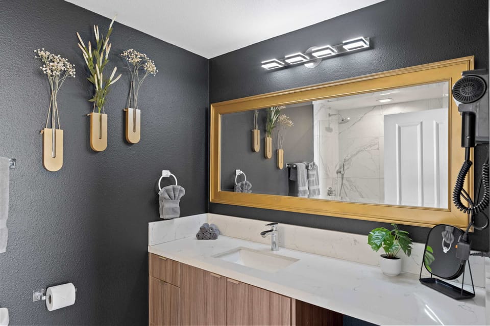 🛁 Dark, moody bath with a gold-framed mirror—a dressing area with boutique-hotel polish.