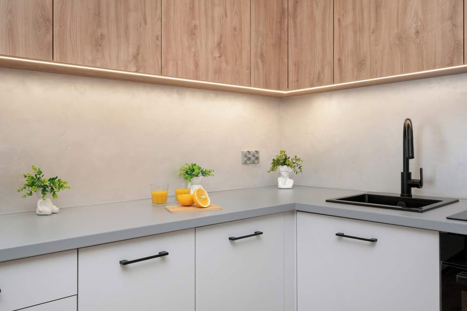 Modern kitchen with wooden cabinets, black countertop, built-in appliances, and under-cabinet lighting.