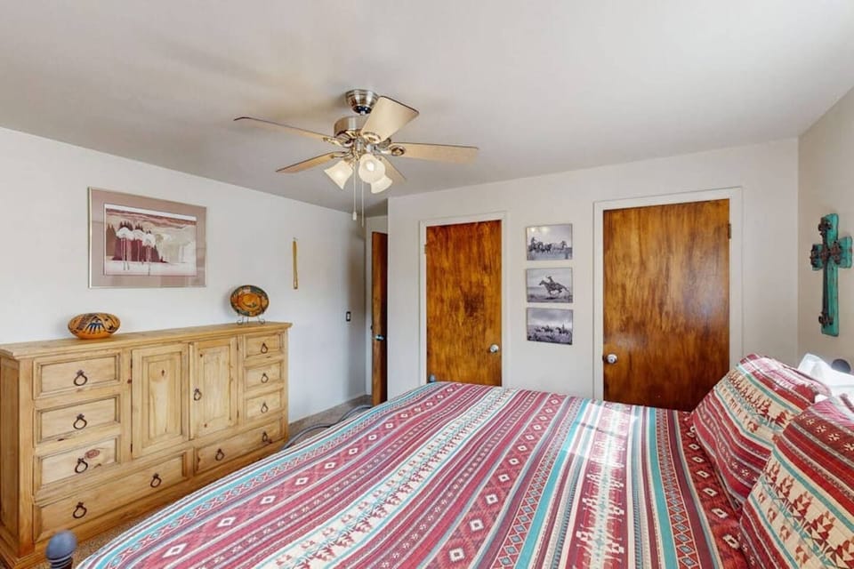 A bedroom furnished with a light wood dresser and a patterned bedspread.