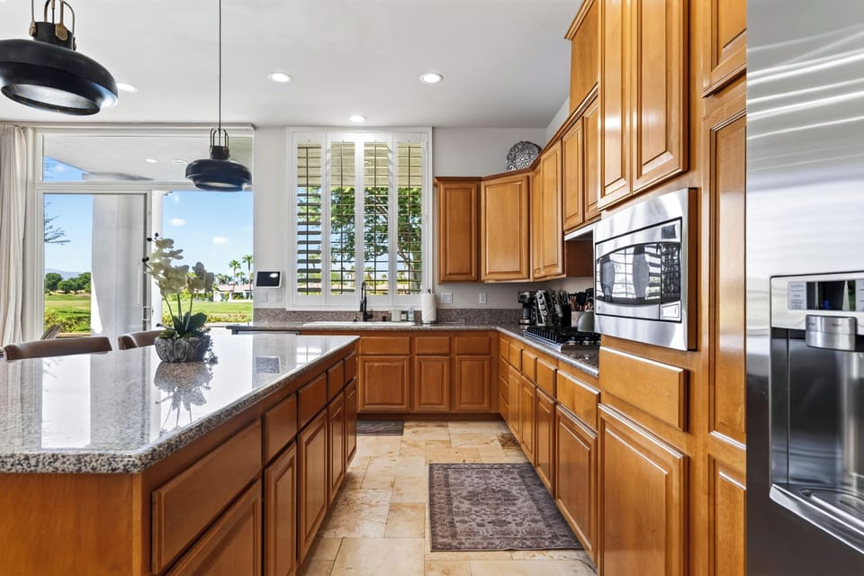 Galley-style kitchen showcases extensive wood cabinetry, granite counters, and built-in stainless appliances.