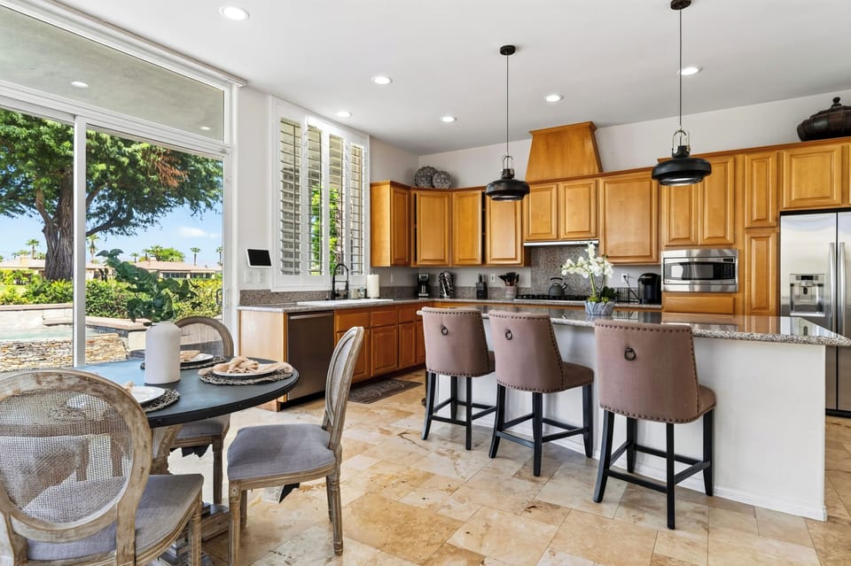 Open kitchen features wood cabinetry, granite island, bar seating, and adjoining breakfast nook.