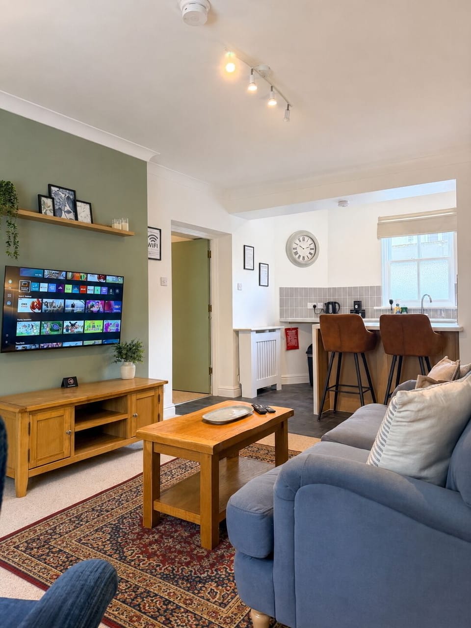 Cozy open-plan lounge with smart TV, breakfast bar, and stylish kitchen