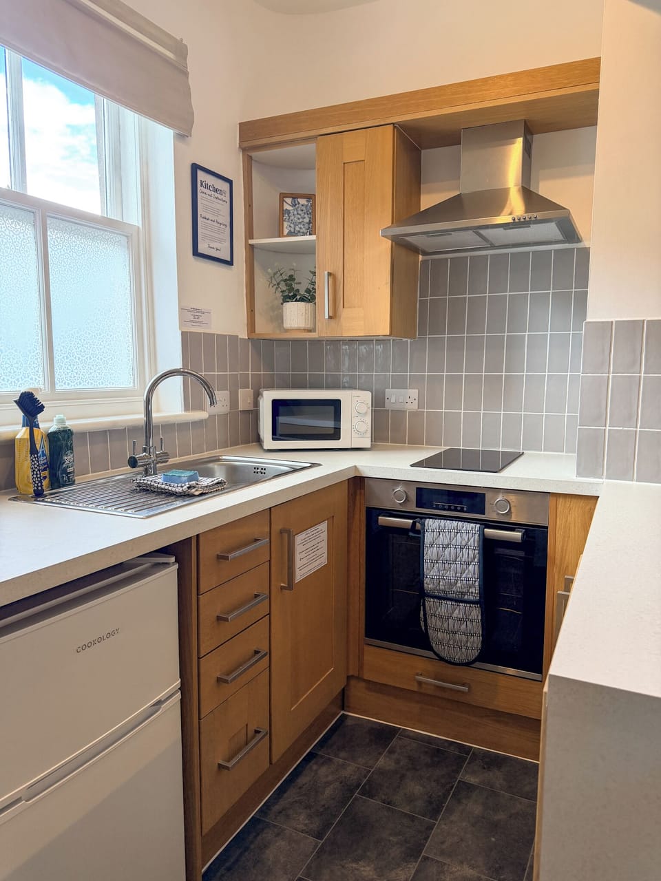 Bright modern kitchenette with oven, hob, microwave, and natural light