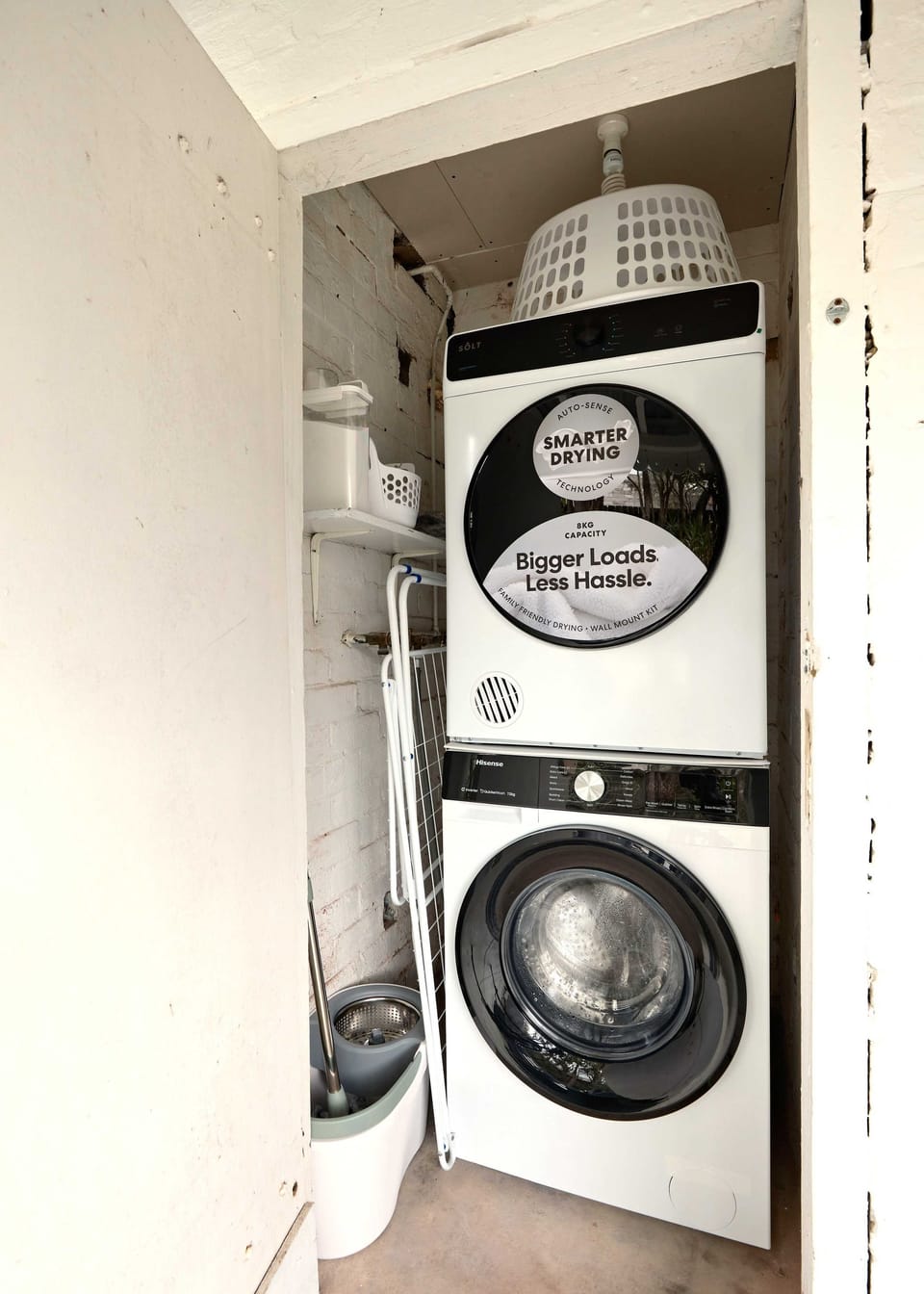 Dedicated laundry closet fitted with a stacked front-loading washer and dryer.