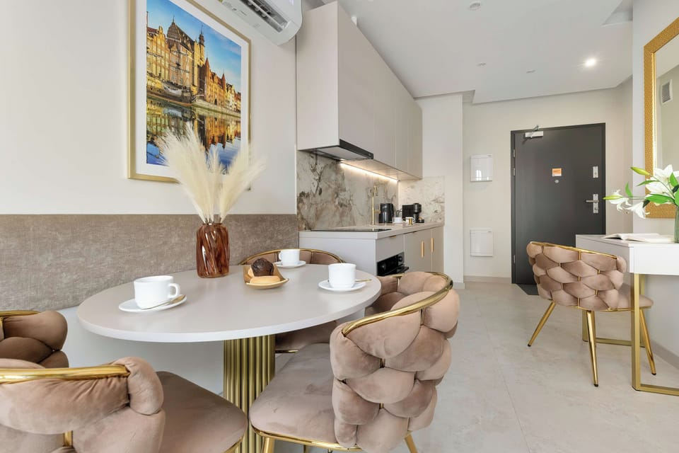 A closer view of the elegant dining area with a round table and plush upholstered chairs. A small decorative arrangement sits on the table beneath a framed artwork.
