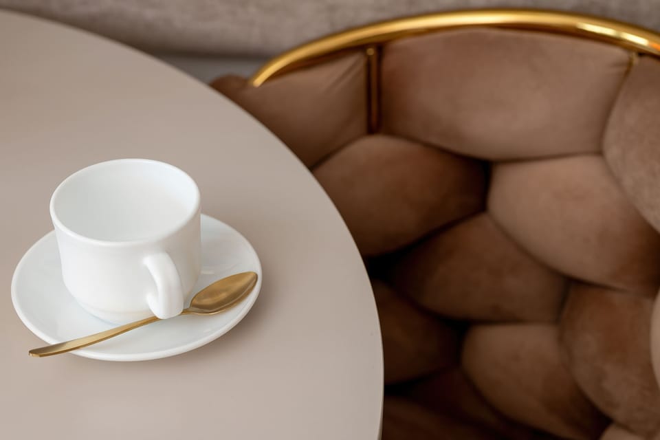 A cup of coffee on a small table beside a comfortable armchair.
