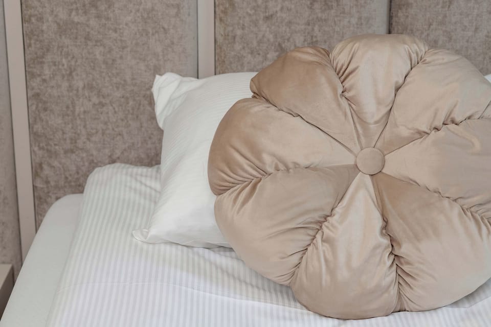 A neatly made bed with decorative pillows and soft neutral bedding.