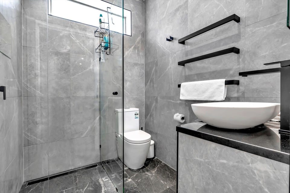 Sleek grey-tiled shower and vessel sink.
