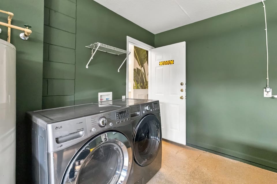 Laundry room with dark green walls, polished concrete floor, and front-loading washer and dryer.