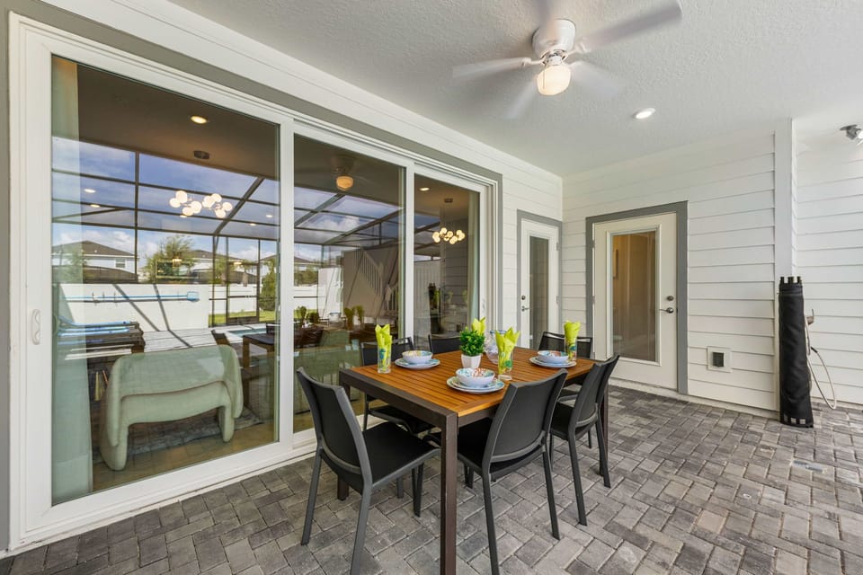 Enjoy alfresco meals on the covered patio with a stylish dining set, screened pool views, and a breezy indoor-outdoor feel made for relaxing together.