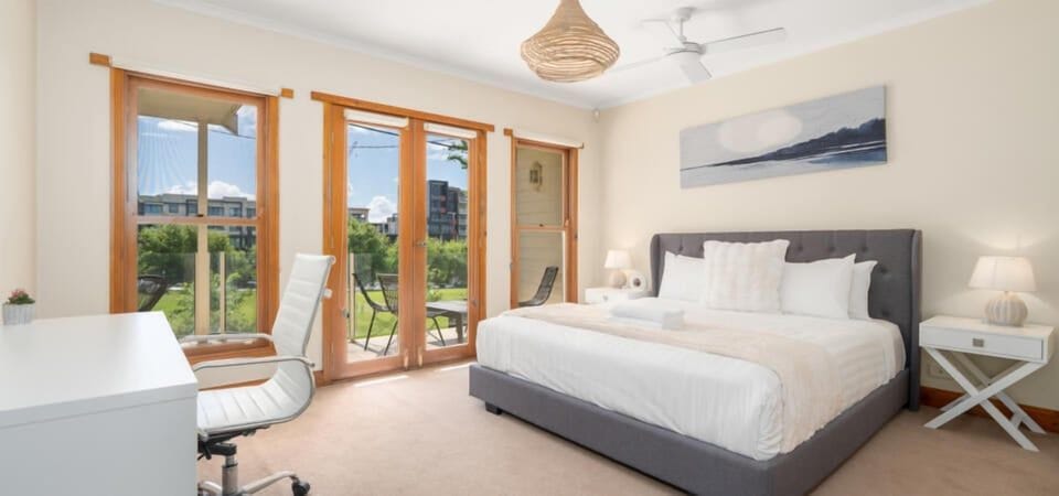 Bright master bedroom with balcony access and natural light.