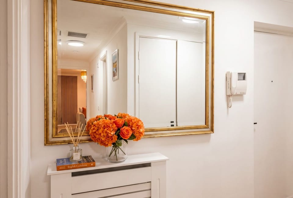 The gilt-framed mirror hangs above a radiator cover by the entrance.