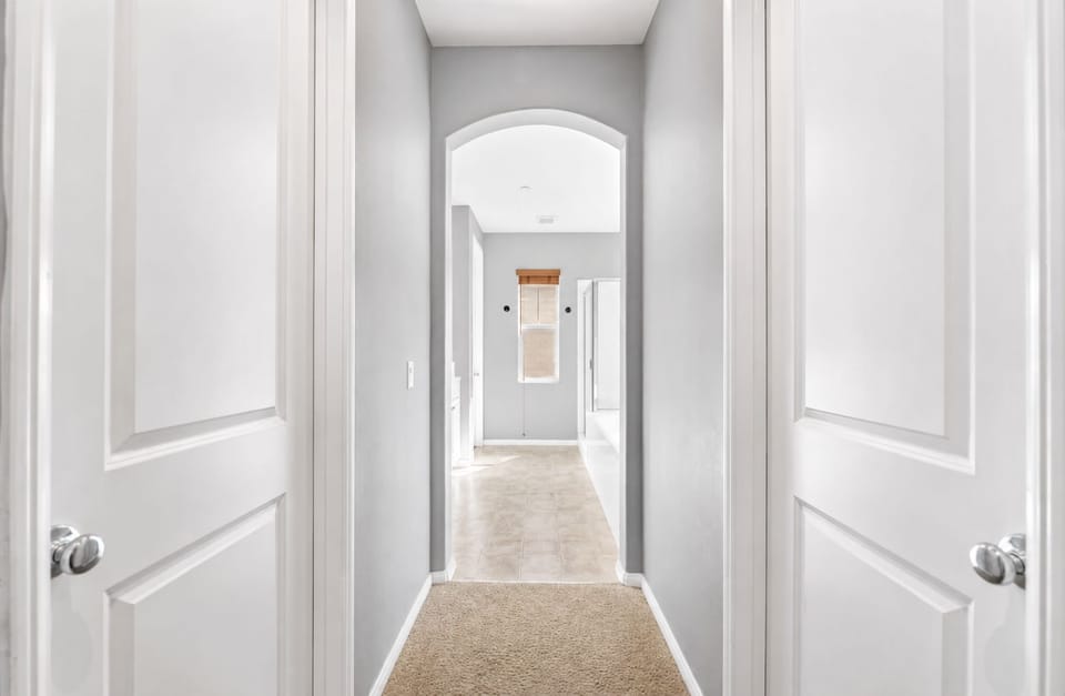 Hallway view with arched entry, soft carpet, and easy access between the bedrooms