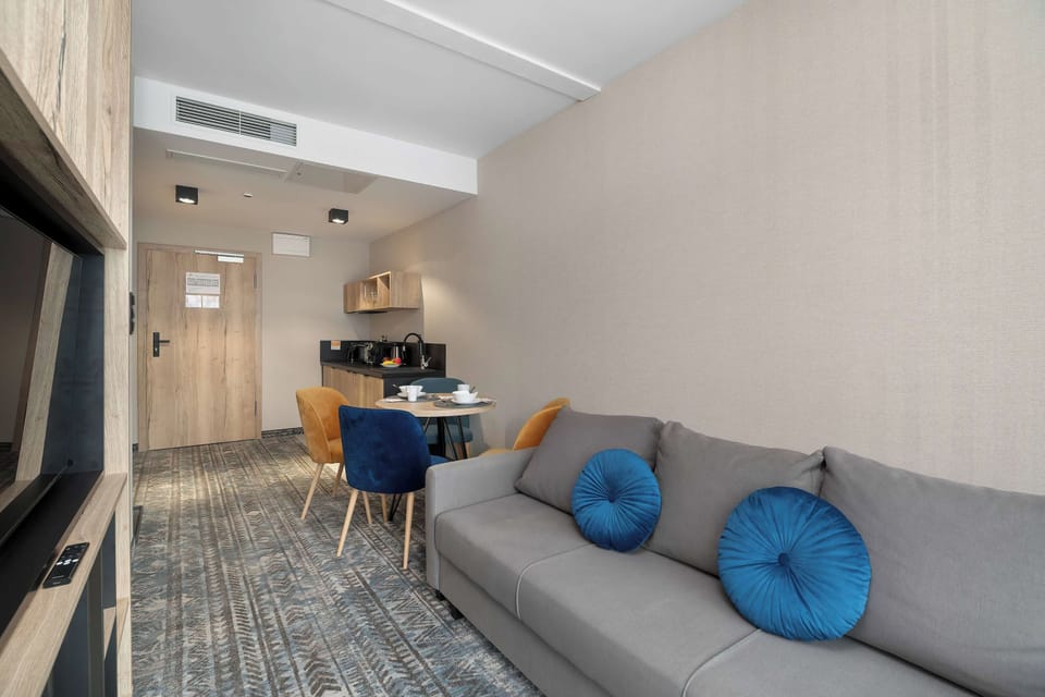 A gray sofa with blue cushions positioned in a comfortable living area. The dining and kitchen zones can be seen in the background.