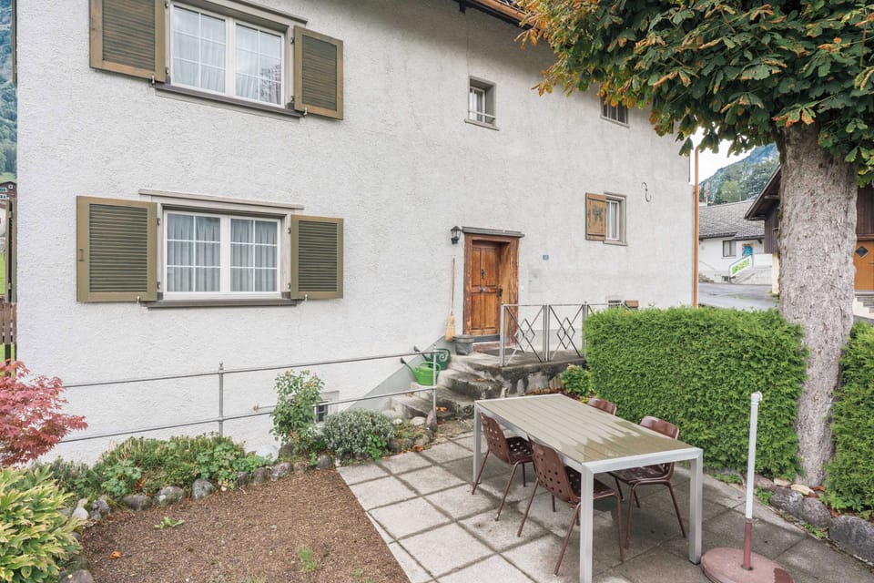 Outdoor seating area beside the traditional house, surrounded by greenery and peaceful village scenery.

