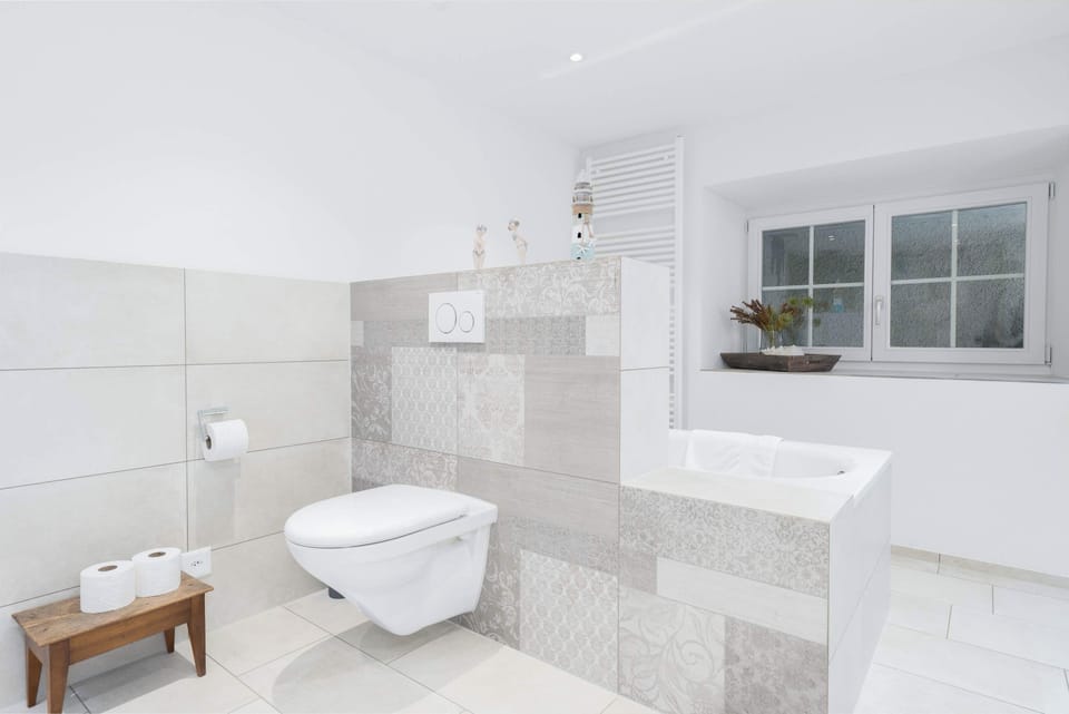 Bright shared bathroom with shower, toilet, sink, and modern finishes.
