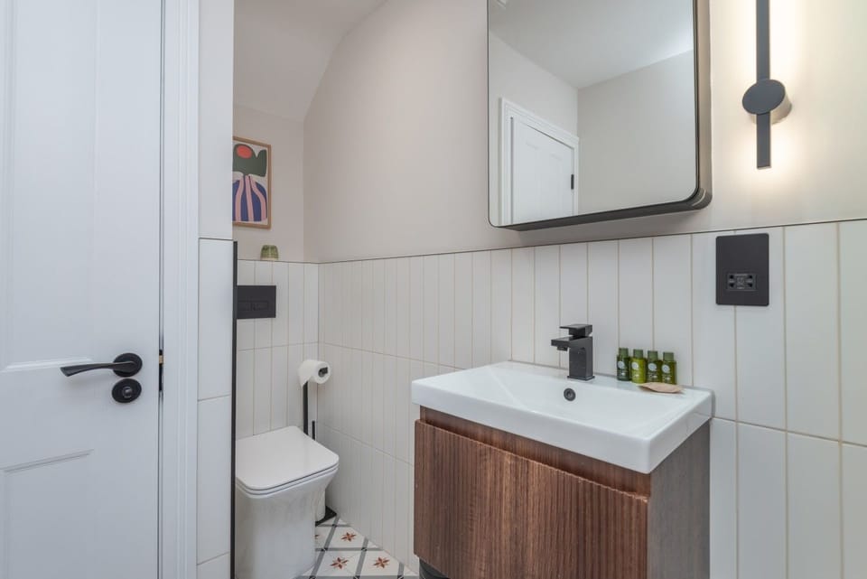 Bright bathroom with vanity sink, mirror and toilet