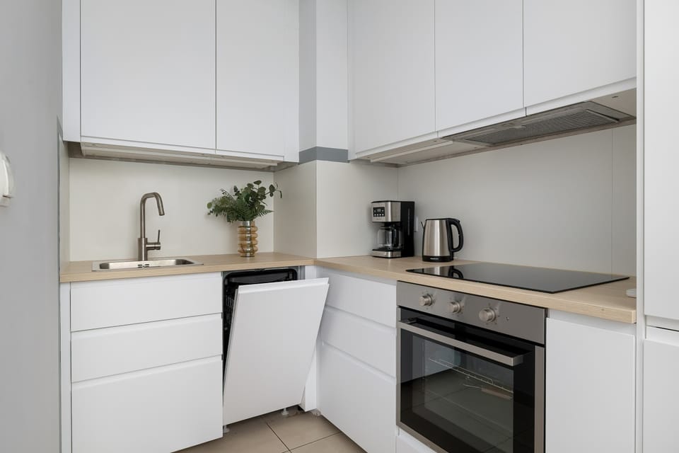 Another view of the modern white kitchen, highlighting the sleek cabinetry, countertop, and built-in appliances.