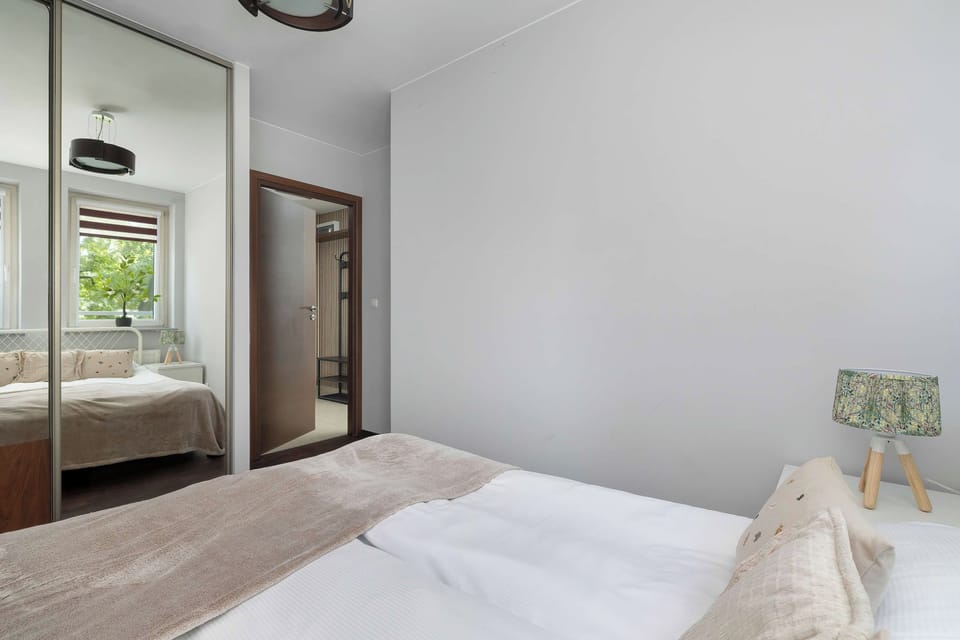 A bright bedroom with a neatly made bed, light-colored walls, and natural light coming through the window.