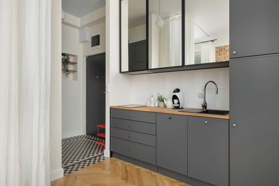 A modern kitchenette with dark cabinets, a countertop, and built-in appliances.