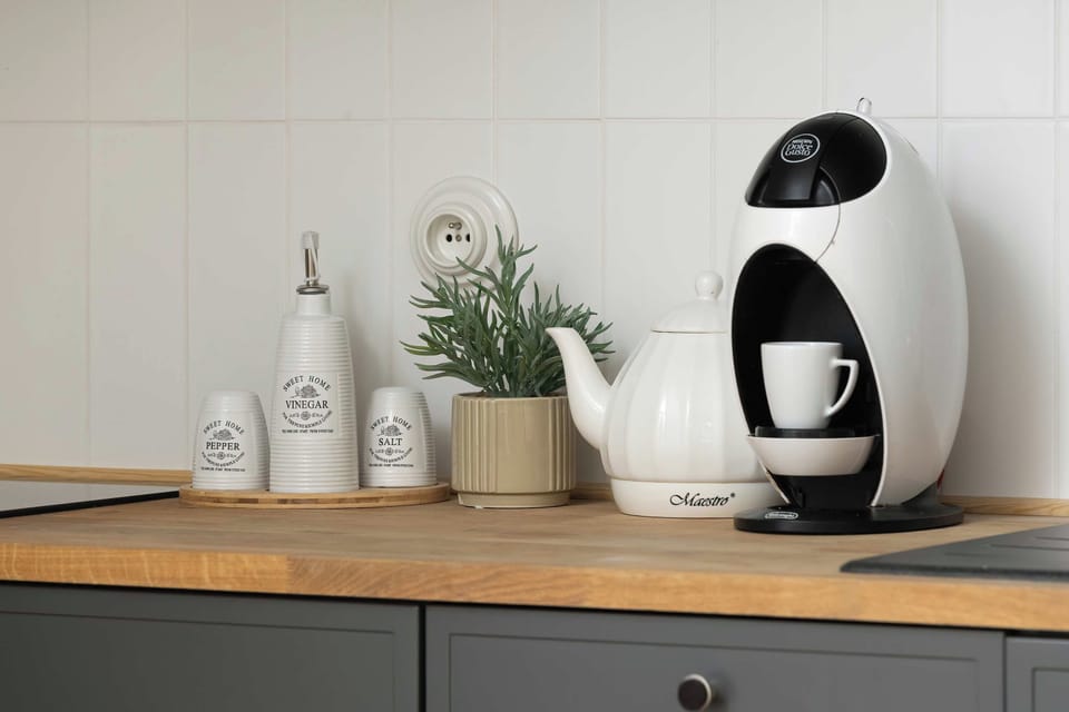 A kitchenette countertop with a coffee machine, decorative vases, and a small plant.