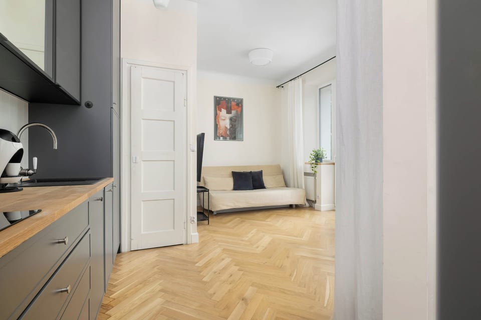 A bright modern interior with a kitchen, light wood flooring, and white walls.