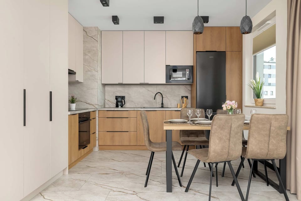 A modern kitchen with light cabinets, built in appliances, and a dining table with chairs. The open layout makes it convenient to prepare meals while staying connected with the rest of the apartment.