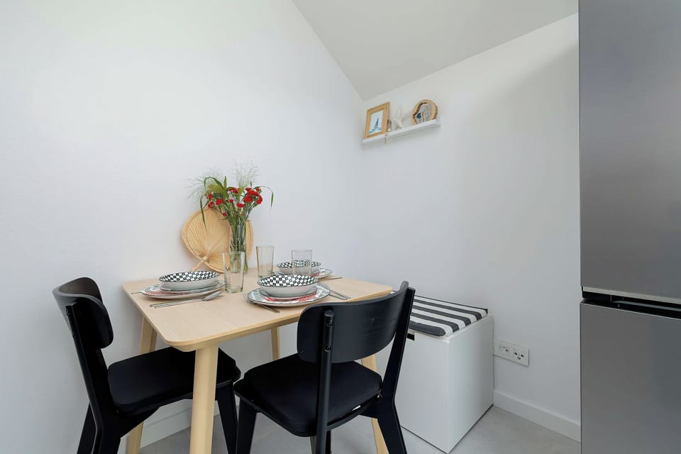A compact dining area with a round table, black chairs, and a vase of flowers.