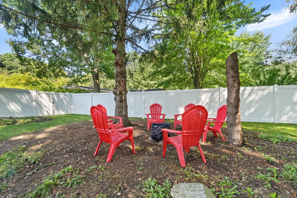 Shaded backyard fire pit area with cozy Adirondack seating